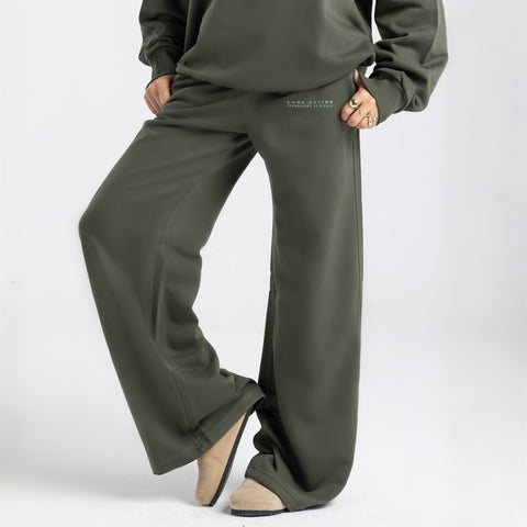 Model wearing the BROWNTOAST Core Flared Sweats from the Core Drop — women’s cotton-lycra flared sweatpants with a mid-rise waist, adjustable drawstring, and subtle seam detailing. Made in Egypt for a soft, flattering, and effortless everyday look. In olive green color.