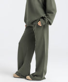 Model wearing the BROWNTOAST Core Flared Sweats from the Core Drop — women’s cotton-lycra flared sweatpants with a mid-rise waist, adjustable drawstring, and subtle seam detailing. Made in Egypt for a soft, flattering, and effortless everyday look. In olive green color.