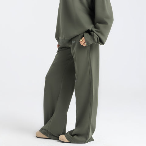 Model wearing the BROWNTOAST Core Flared Sweats from the Core Drop — women’s cotton-lycra flared sweatpants with a mid-rise waist, adjustable drawstring, and subtle seam detailing. Made in Egypt for a soft, flattering, and effortless everyday look. In olive green color.