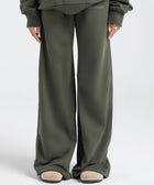 Model wearing the BROWNTOAST Core Flared Sweats from the Core Drop — women’s cotton-lycra flared sweatpants with a mid-rise waist, adjustable drawstring, and subtle seam detailing. Made in Egypt for a soft, flattering, and effortless everyday look. In olive green color.