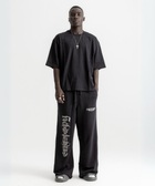 Unisex black baggy sweatpants with chunky waistband, raw pocket detailing, and light grey grunge print.