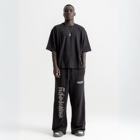 Unisex black baggy sweatpants with chunky waistband, raw pocket detailing, and light grey grunge print.
