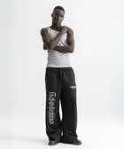 Unisex black baggy sweatpants with chunky waistband, raw pocket detailing, and light grey grunge print.