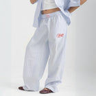 Unisex wide-leg striped cotton pants in ocean blue and white, relaxed slouchy fit, modeled with casual summer outfit.