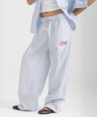 Unisex wide-leg striped cotton pants in ocean blue and white, relaxed slouchy fit, modeled with casual summer outfit.