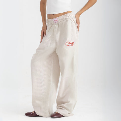 Unisex wide-leg striped cotton pants in beige and white, relaxed slouchy fit, modeled with casual summer outfit.