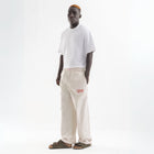 Unisex wide-leg striped cotton pants in beige and white, relaxed slouchy fit, modeled with casual summer outfit.