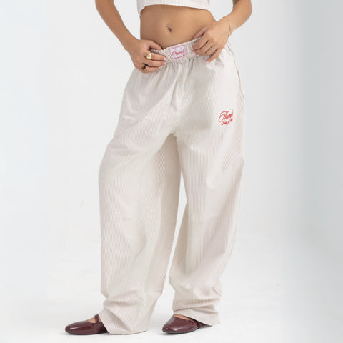 Unisex wide-leg striped cotton pants in beige and white, relaxed slouchy fit, modeled with casual summer outfit.