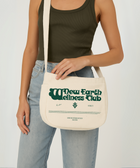 Limited edition canvas crossbody bag in beige featuring side pocket, inner compartments, and front and back design in dark green.