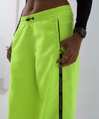 Unisex wide-fit waterproof pants in soft polyester with side stripe logo and adjustable waistband.