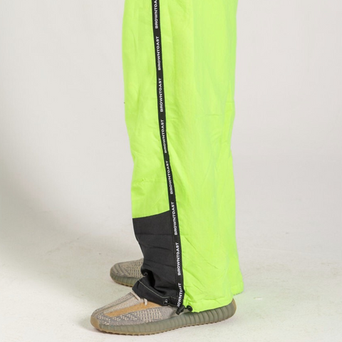 Unisex wide-fit waterproof pants in soft polyester with side stripe logo and adjustable waistband.