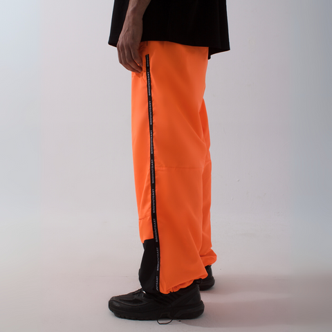 Unisex wide-fit waterproof pants in soft polyester with side stripe logo and adjustable waistband.