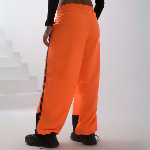 Unisex wide-fit waterproof pants in soft polyester with side stripe logo and adjustable waistband.
